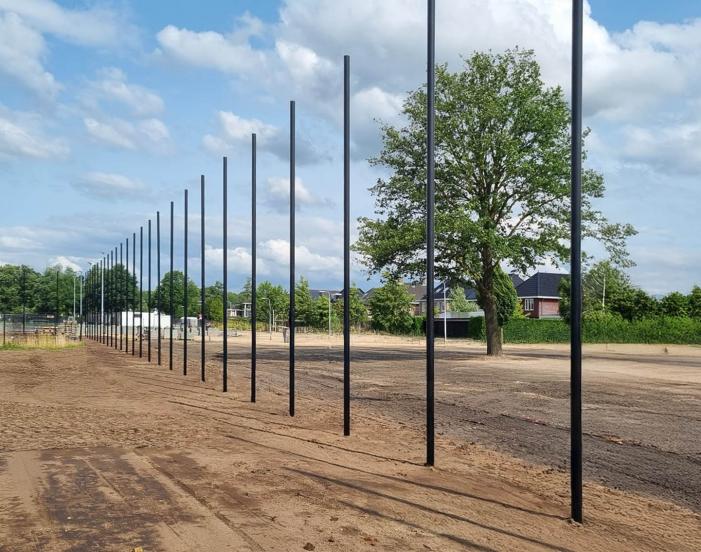 A row of black fence posts set out along the line before the panels go on